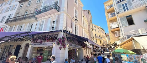 A street with outdoor seating, a bakery, and a variety of shops.