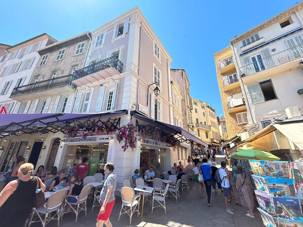 Un carrer amb terrasses a l'exterior, una forneria i diversos comerços.