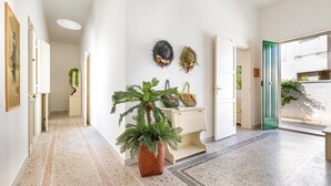 A hallway with a potted plant, a white console table, and a door with a green frame. - 2068 Villa Marina Salentina (Porto Cesareo)