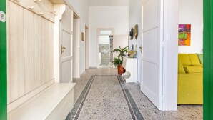 A hallway with a bench, a potted plant, and a yellow couch. - 2068 Villa Marina Salentina (Porto Cesareo)