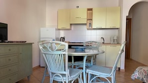 Una cocina compacta con una mesa de comedor y sillas, un refrigerador y un televisor.