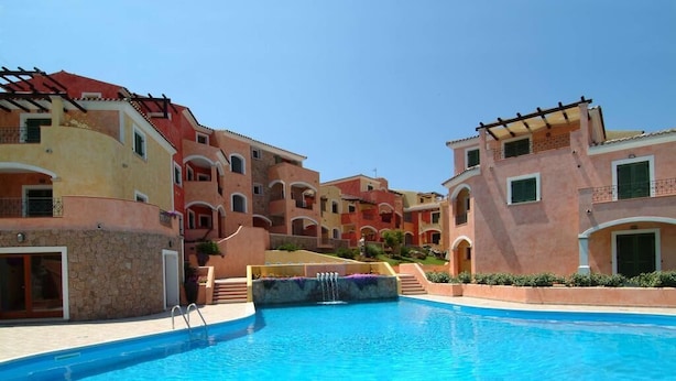 Una piscina rodeada de edificios altos con balcones y un cielo despejado.