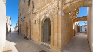 A narrow street with stone buildings, an open doorway, and a clear blue sky. - 2095 Palazzo Benedetto Campo (Torricella)