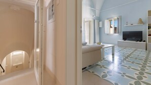 A spacious living area with a high ceiling, a flat-screen TV, and a patterned floor. - 2095 Palazzo Benedetto Campo (Torricella)