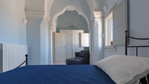 A bedroom with a bed, a chair, and a window. - 2095 Palazzo Benedetto Campo (Torricella)