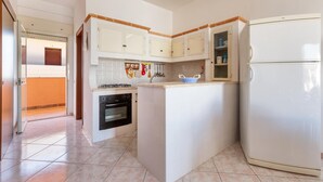 A compact kitchen with white cabinets, a built-in oven, and a refrigerator. - 1930 Residence La Primula (Manduria)