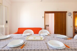 A dining area with a table set for four, white chairs, and a red cushion. - 1930 Residence La Primula (Manduria)