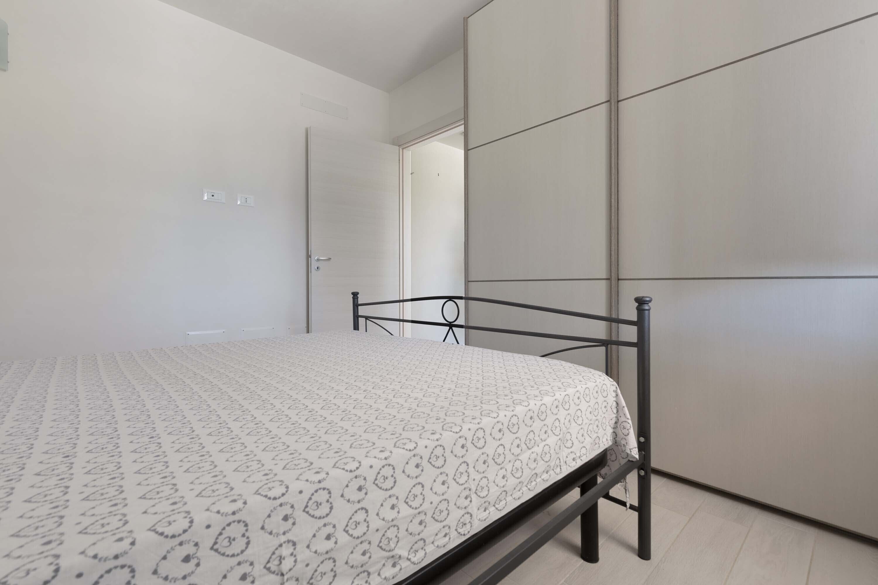 A bedroom with a bed, a wardrobe, and a door.