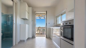 A modern kitchen with a large oven, a glass shower enclosure, and a view through an open door. - 2097 Villa Regina Dello Ionio (Manduria)