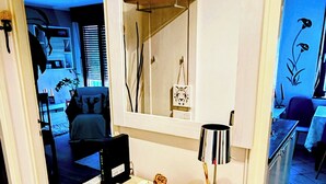 A small kitchen with a white cabinet, a countertop, and a mirror above it. There is a small table with a lamp and decorative items on the countertop. - Cozy Seaside Retreat in Rijeka (Rijeka)