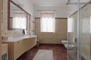 A bathroom with a large mirror, a sink, a toilet, and a shower area.