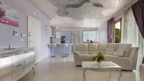 A modern living room with a sofa, coffee table, and a kitchen in the background. - 2088 Villa Marilda (Martina Franca)