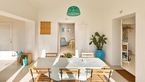 A modern dining area with a large table, chairs, and a hanging green lamp. - 2124 I Colmi Trulli Suites (Martina Franca)