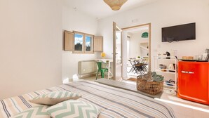 A bedroom with a bed, a desk, a chair, a TV, and a red cabinet. - 2124 I Colmi Trulli Suites (Martina Franca)