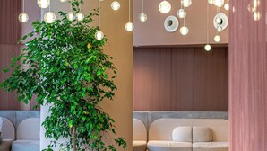 Un vestíbulo moderno con lámparas esféricas colgantes, un árbol en maceta y una zona de estar.