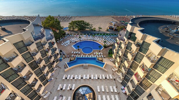 Un hotel con piscina, tumbonas y vistas a la playa.