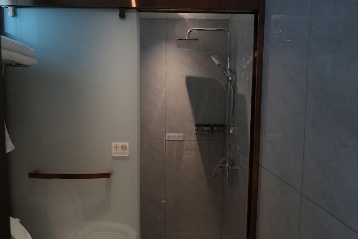 Une salle de bain moderne avec une douche à parois de verre, des toilettes et un porte-serviettes.