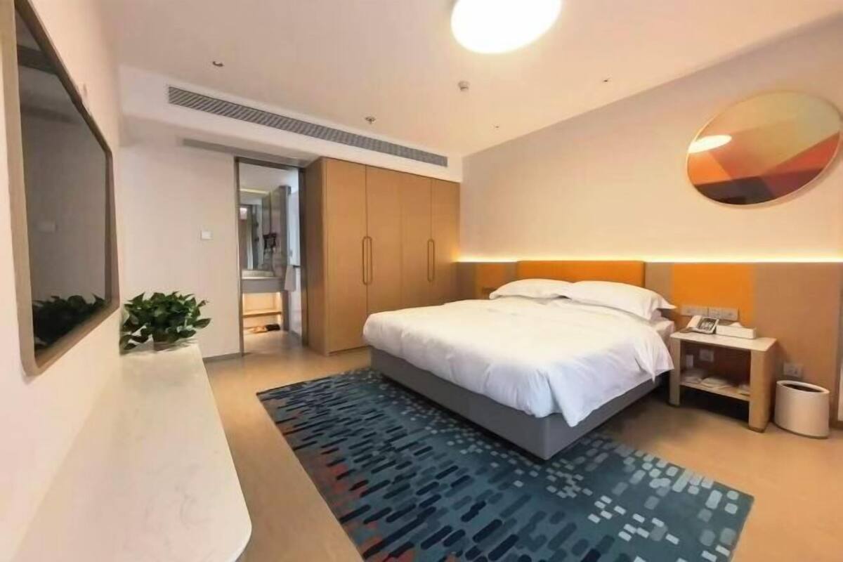 Una habitación de hotel moderna con cama, mesita de noche y un espejo grande.