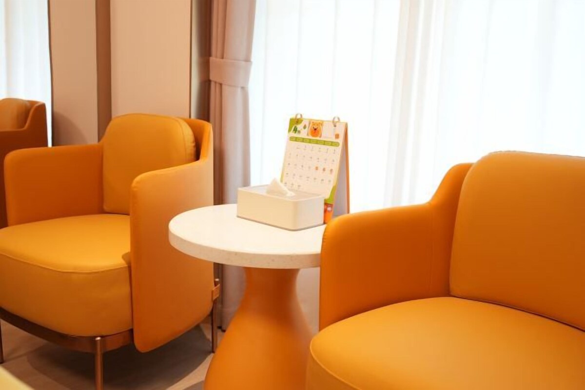 Une pièce avec deux fauteuils orange et une petite table blanche sur laquelle se trouve un calendrier.