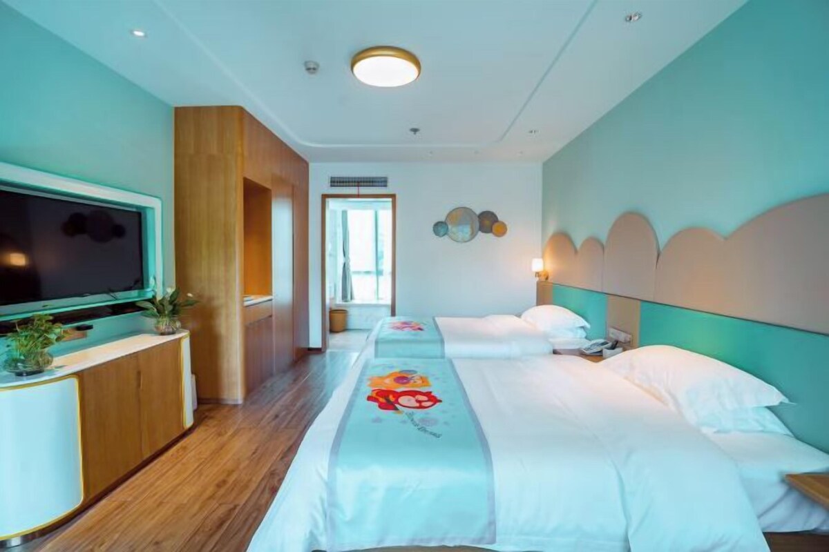 Une chambre d’hôtel avec deux lits, une télévision, une armoire en bois et vue sur le couloir.