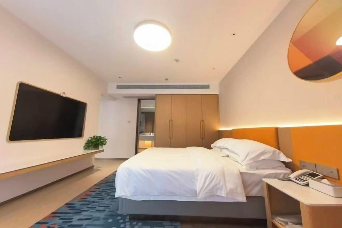 Une chambre d’hôtel équipée d’un lit, d’une table de chevet, d’une télévision et d’un miroir.