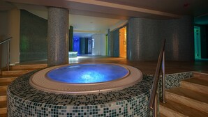 Ein großes Hallenbecken mit Mosaikfliesen und Holzboden.