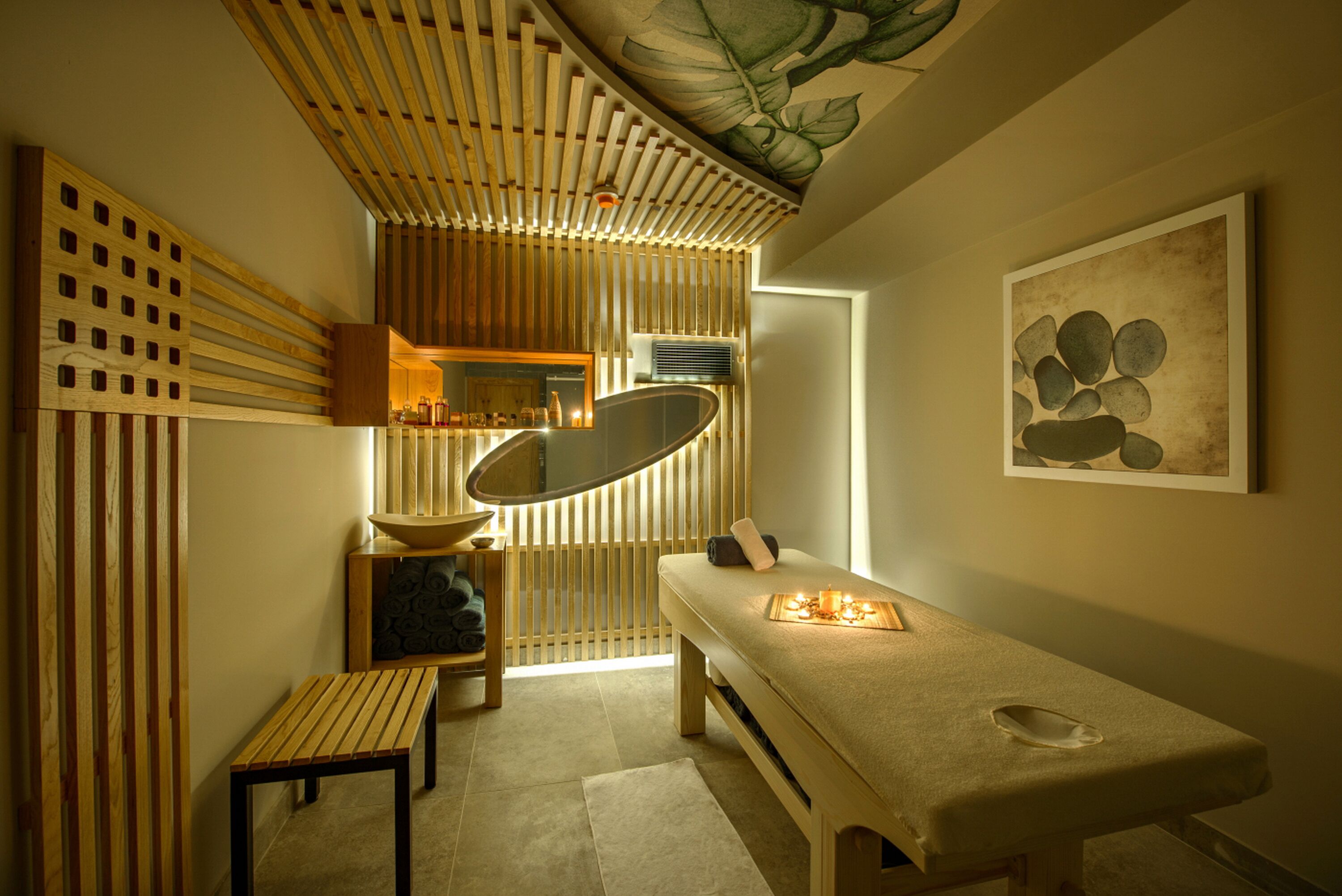 A modern spa room with a wooden slatted ceiling, a large mirror, a massage table, and a wall-mounted artwork.