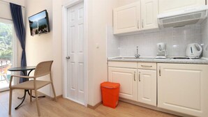 Una cocina compacta con armarios blancos, una encimera con cafetera y un pequeño cubo de basura.