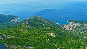 Uma cidade costeira com montanhas ao fundo, apresentando uma mistura de edifícios residenciais e comerciais, estradas e uma vista clara do mar.