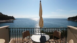 A balcony with a table and chairs overlooking a body of water, with mountains in the distance. - Sea View Apartment 33 (Drvenik)