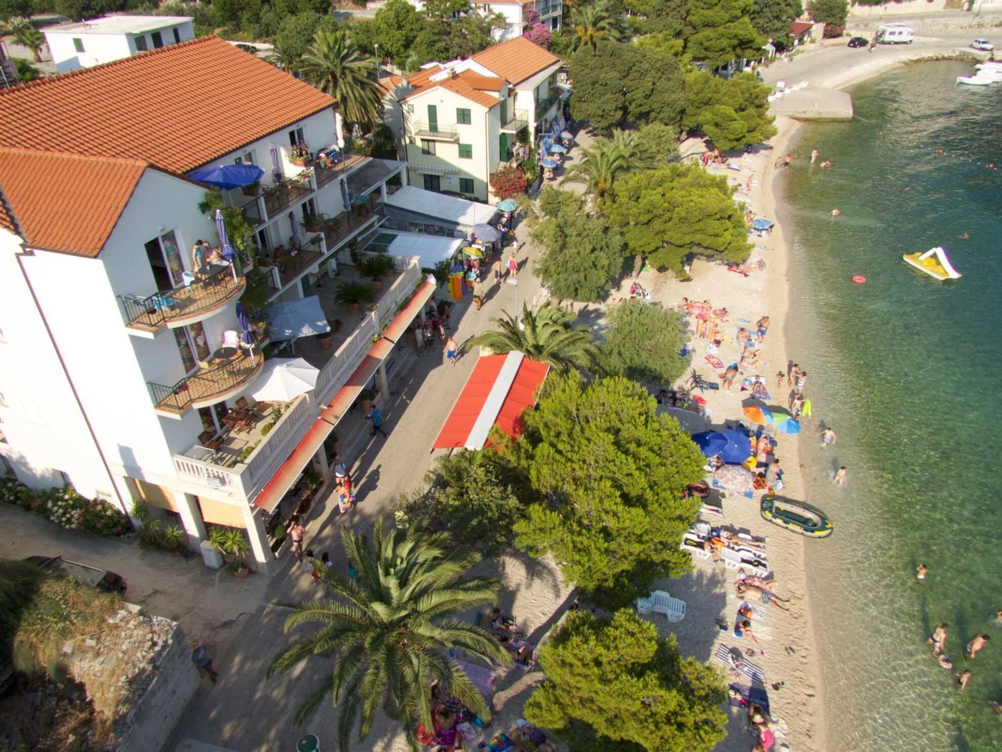 A coastal hotel with a beach view, multiple balconies, and a swimming area.