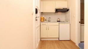 Una cucina compatta con mobili bianchi, forno integrato e lavastoviglie.