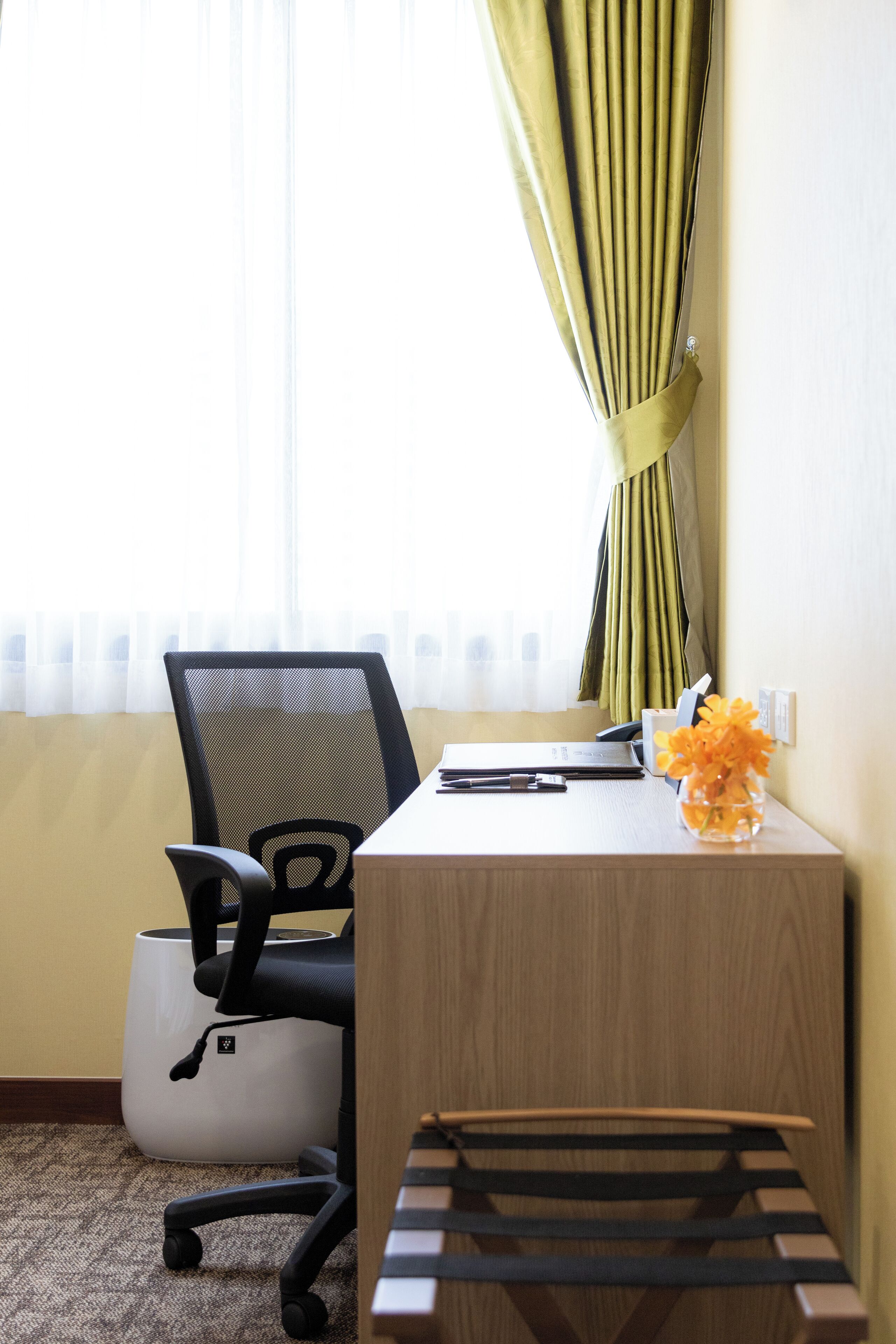 Une pièce comprenant un bureau, une chaise et une petite table sur laquelle est posé un vase de fleurs.