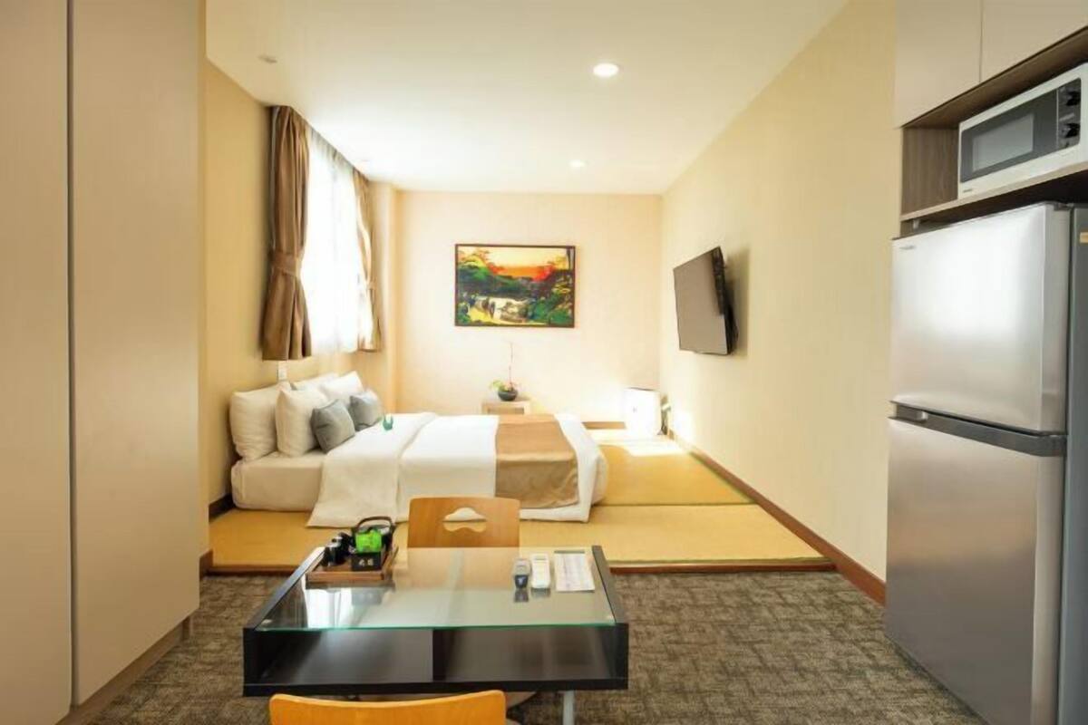 Une chambre d’hôtel équipée d’un lit, d’un bureau, d’une télévision et d’un réfrigérateur.