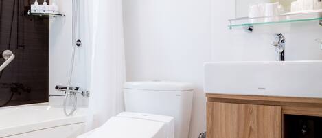A modern bathroom with a bathtub, toilet, and glass shelf above the sink.