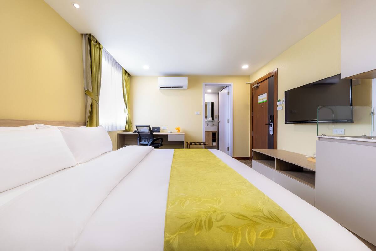 Une chambre d’hôtel équipée d’un lit, d’un bureau, d’une chaise, d’une télévision et d’un appareil de climatisation.