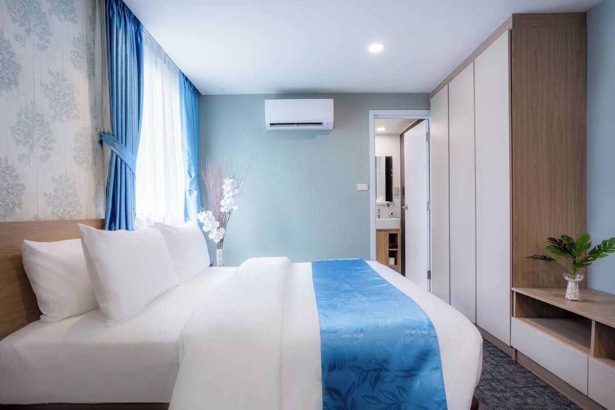Une chambre d’hôtel avec un lit, une armoire, un miroir et une petite plante.