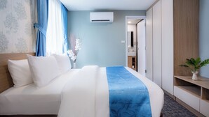 Habitación de hotel con cama, armario, espejo y una planta pequeña.