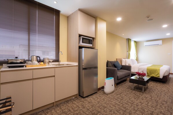 Una habitación de hotel compacta con kitchenette, un sofá, una cama y una pequeña mesa.