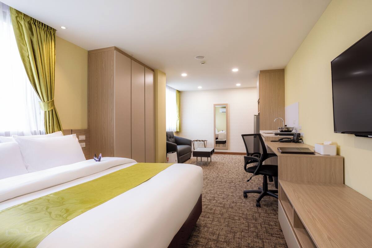 Une chambre d’hôtel avec un grand lit, un bureau, une chaise, une télévision et un miroir.