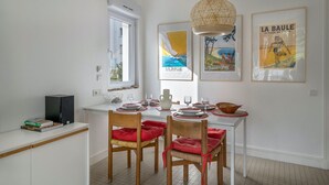 A dining area with a white table set for four, red cushioned chairs, a woven pendant light, and framed posters on the wall. - 200m from the beach, cosy house for 4 (La Baule-Escoublac)
