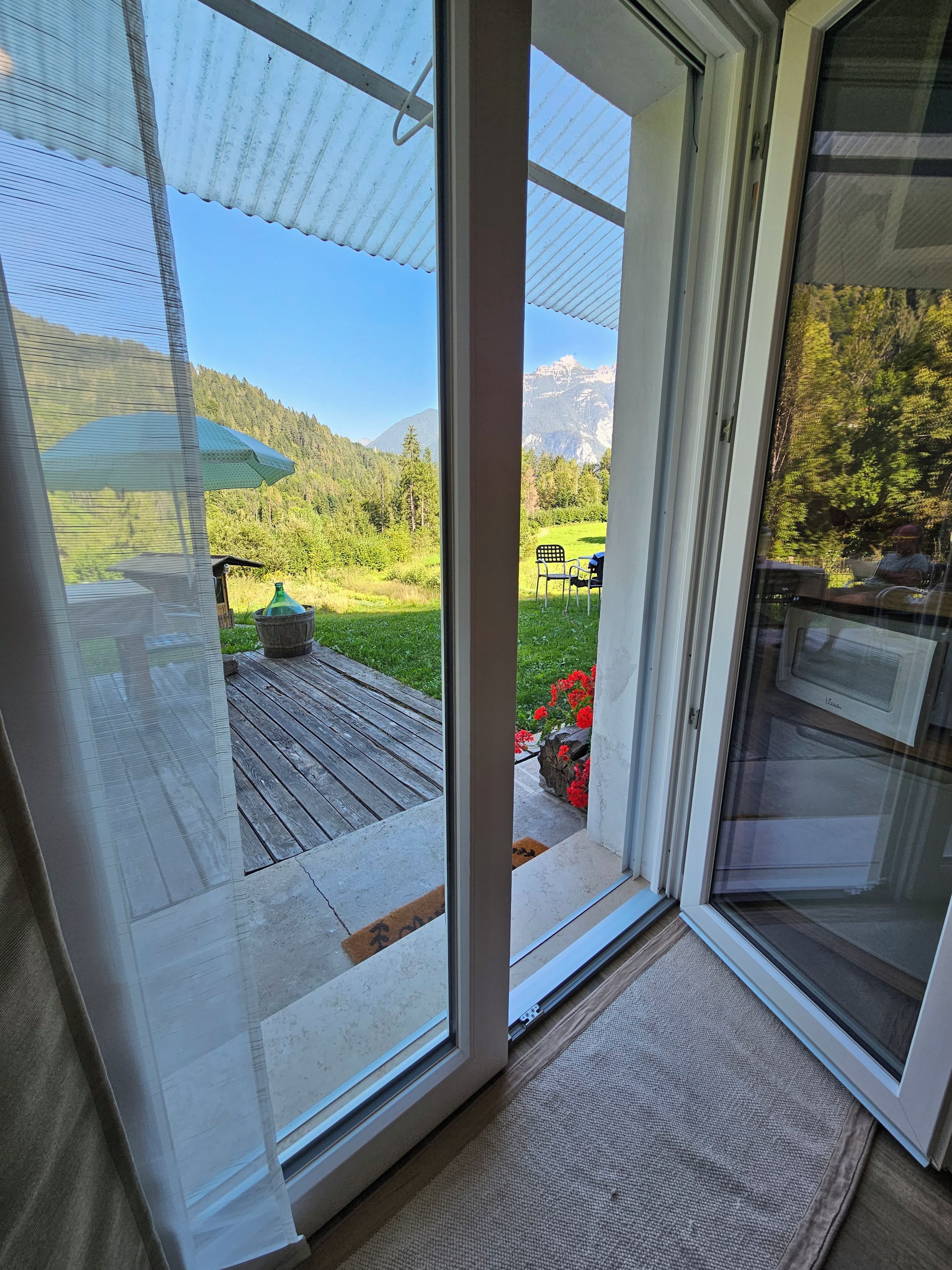 A sliding glass door leading to an outdoor deck with a view of a mountainous landscape.