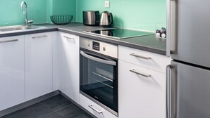 Eine moderne Küche mit weißen Schränken, einem Edelstahlkühlschrank und einer grünen Spritzschutzwand.