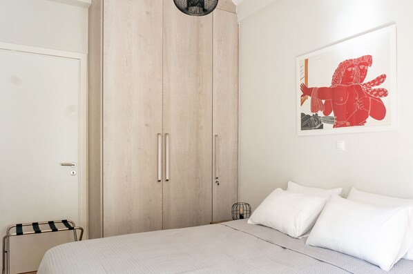 Ein Schlafzimmer mit einem Bett, einem Kleiderschrank und einem an der Wand hängenden Kunstwerk.