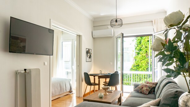 Ein modernes Wohnzimmer mit einer Couch, einem Esstisch und einem an der Wand befestigten Fernseher.