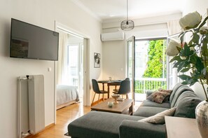 Ein modernes Wohnzimmer mit einer Couch, einem Esstisch und einem an der Wand befestigten Fernseher.