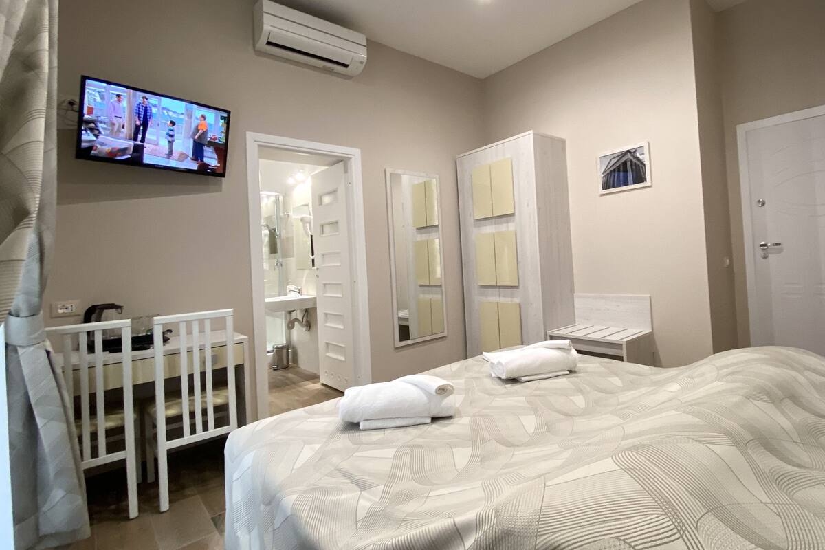 A hotel room with a bed, a TV, a desk, and a wardrobe.