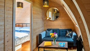 Une chambre confortable située dans les combles, avec un lit, un canapé, une table basse sur laquelle se trouvent un livre et des fleurs, et deux lampes suspendues.