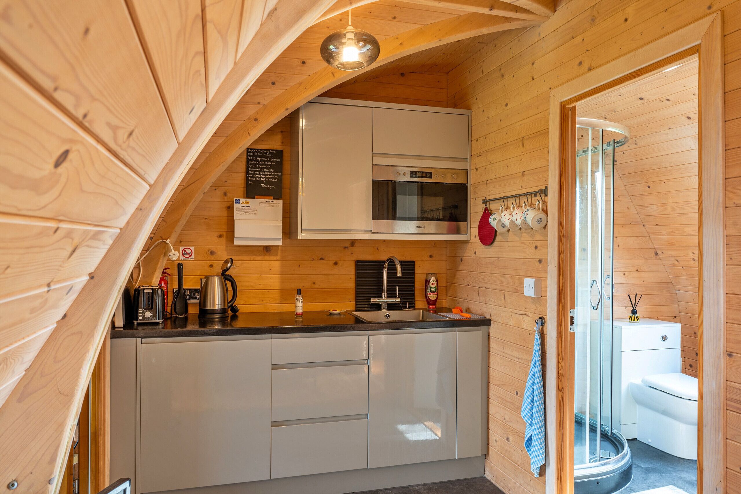 Une cuisine de taille réduite équipée d’un four à micro-ondes, d’un évier et de placards.