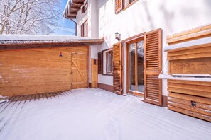 A snow-covered wooden deck with a sliding glass door and a wooden gate.